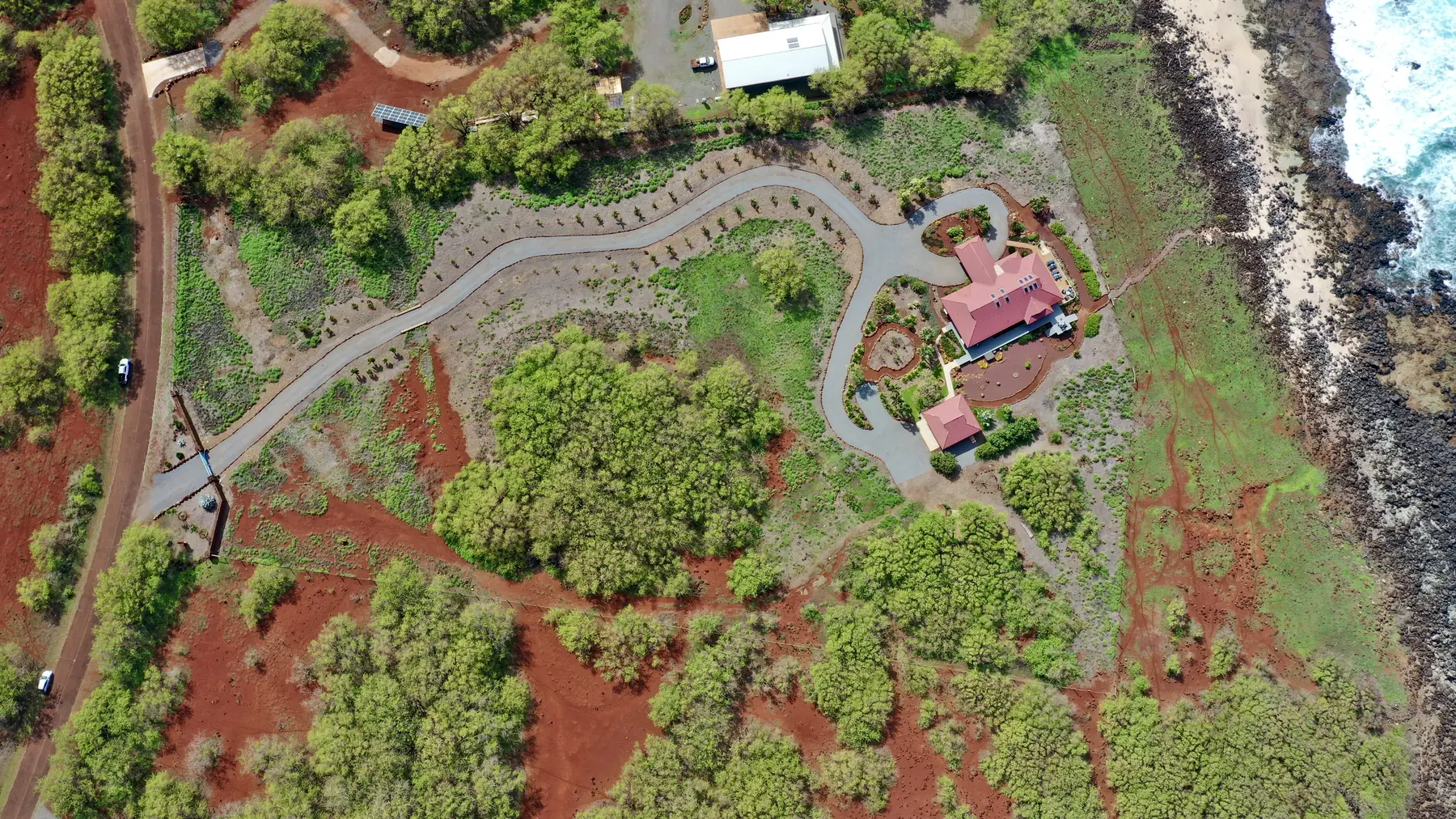 Overhead drone view of an ocean-view estate on red Molokaʻi earth